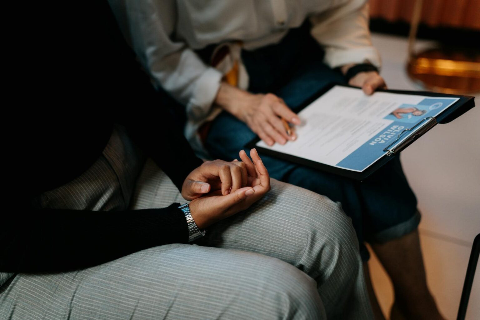 person in white long sleeve shirt holding a clipboard with resume